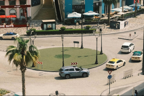 Aerial view of a lively roundabout in Dubai, showcasing colorful vehicles and surrounding architecture