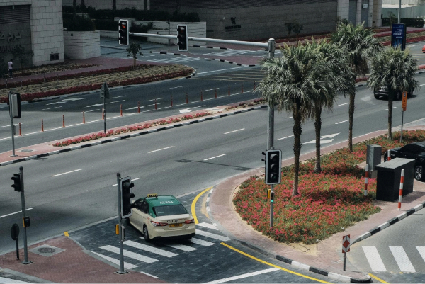 Aerial view of a modern street intersection in Dubai featuring palm trees and a taxi