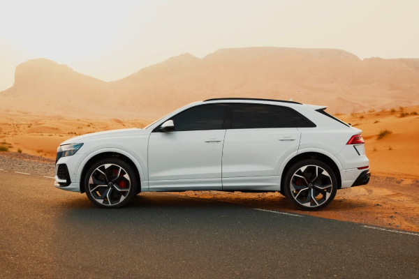 A sleek white SUV parked on a desert road at sunset