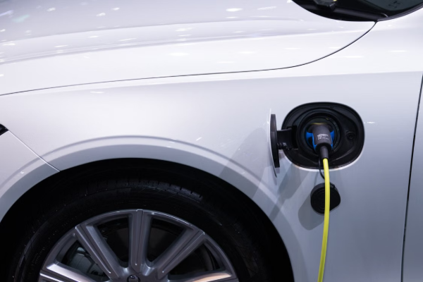 A white electric car is plugged in for charging, close-up view of the charging port