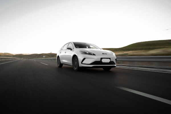  A modern white car drives on an open highway at dawn, highlighting sleek design and open road adventure