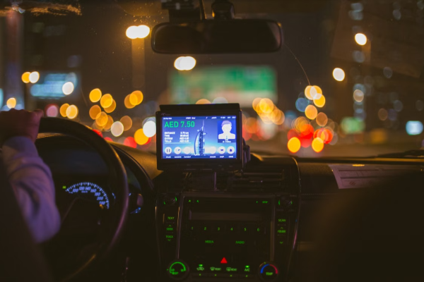 Experience a nighttime taxi ride in Dubai with bokeh city lights and focus on the dashboard and screen