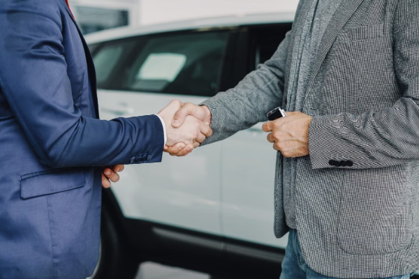 صورة لرجلين يتصافحان في معرض للسيارات بعد إتمام اتفاق
