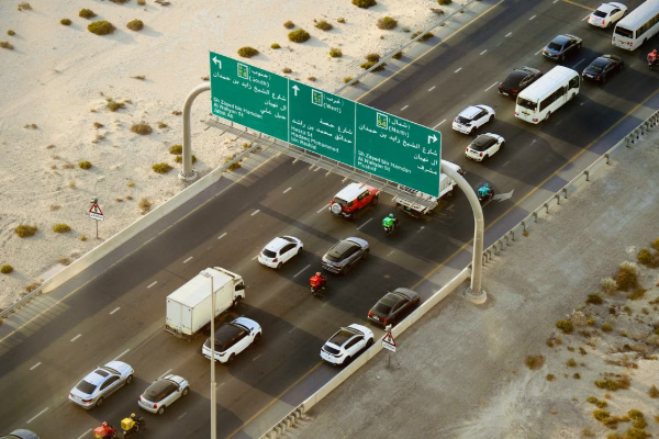 Aerial shot of vehicles on a busy highway in Dubai, capturing road signs and desert surroundings