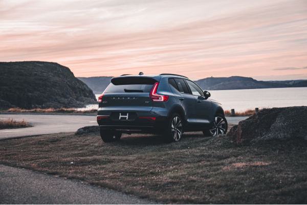  A Volvo XC40 SUV parked near a scenic bay during a serene sunset, highlighting its elegant design and outdoor backdrop